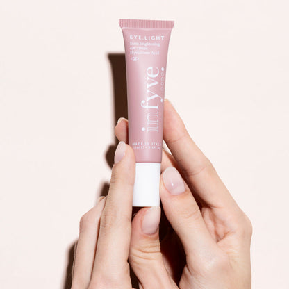 Mani che tengono EYE.LIGHT Contorno Occhi INFYVE Beauty – crema illuminante con Caffeina e Inositolo 15ml